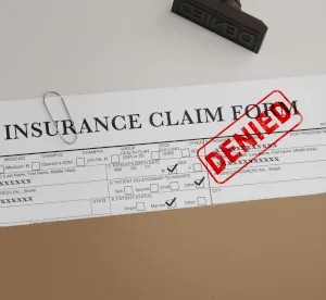 paper work in a folder that says an insurance claim was denied